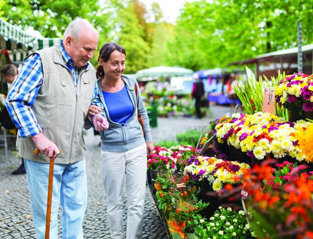 franchisee opportunity senior care provider and a client examine flowers at a market examining flowers