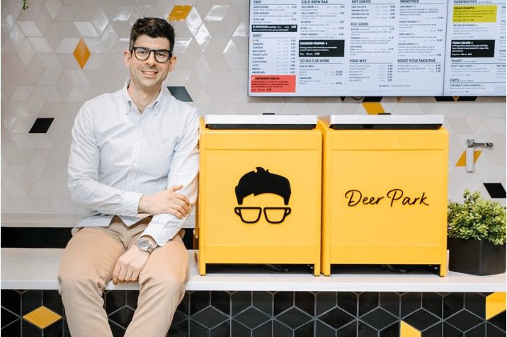 Guy in glasses sitting next to yellow boxes with image of a man in glasses on box