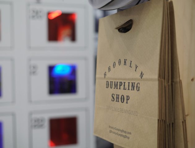 Brooklyn Dumpling Shop bag in front of automat in restaurant.