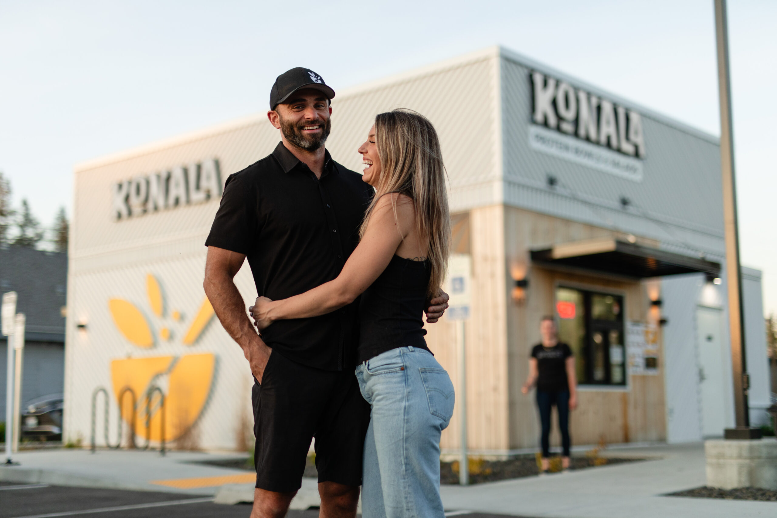 Trace and Jammie Miller standing together and smiling in front of a Konala restaurant