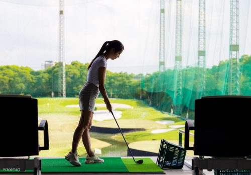 women hitting a golf ball off of a golf range 