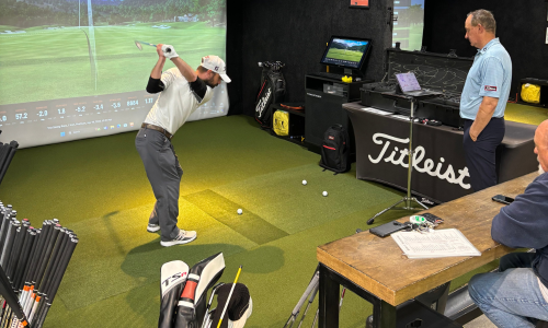 A swing bays golf member getting a golf lesson and swinging a club at indoor golf simulator