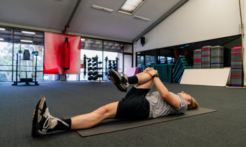 A person laying on the floor stretching their leg